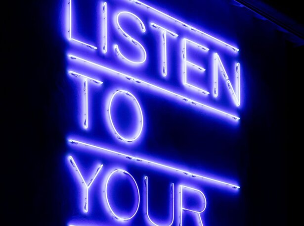 Neonkunstwerk von Maurizio Nannucci mit dem Text 'LISTEN TO YOUR EYES' in blauer Schrift auf schwarzem Hintergrund in Bad Saulgau