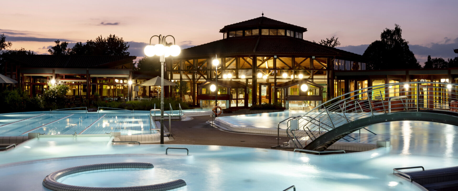 Thermalbad Sonnenhof-Therme bei Dämmerung mit beleuchteten Außenpools, einem modernen Gebäude im Hintergrund und entspannter Atmosphäre.