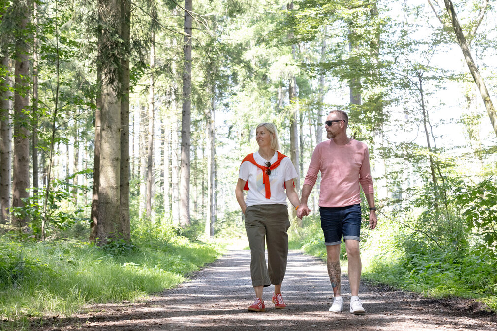 Ein Paar spaziert händchenhaltend durch den Wald.