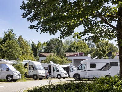 Ein Wohnmobilstellplatz mit mehreren Fahrzeugen.